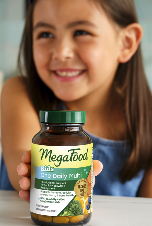 A girl holding MegaFood Kids One Daily Multivitamins