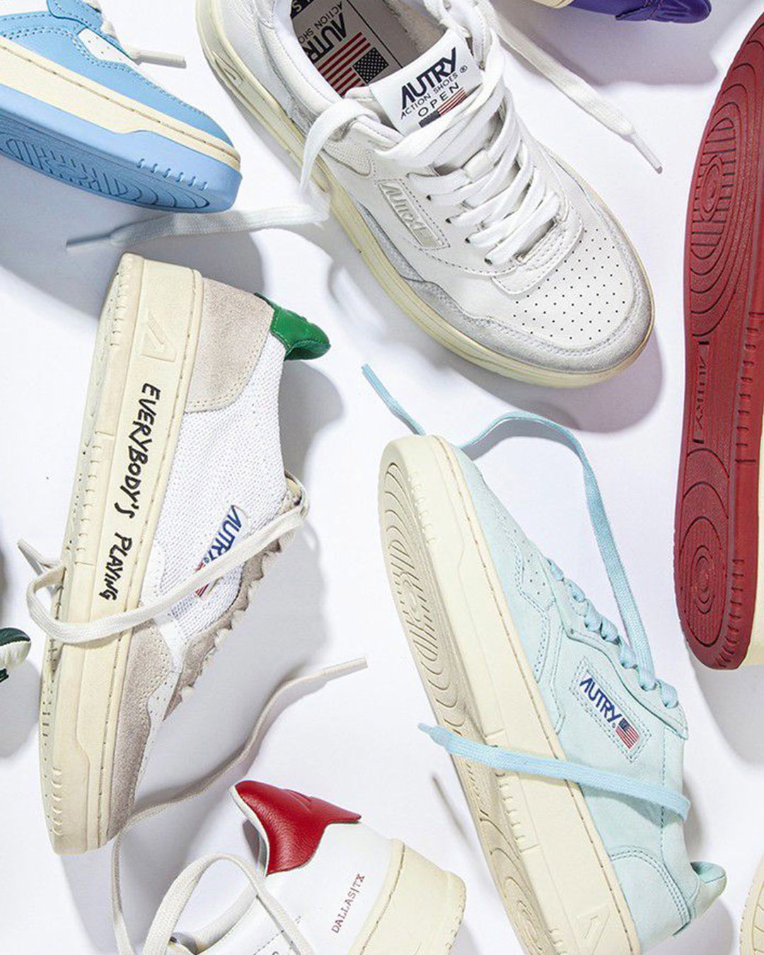 Flat lay of pastel and white retro low-top sneakers (Autry) with untied laces on a white background