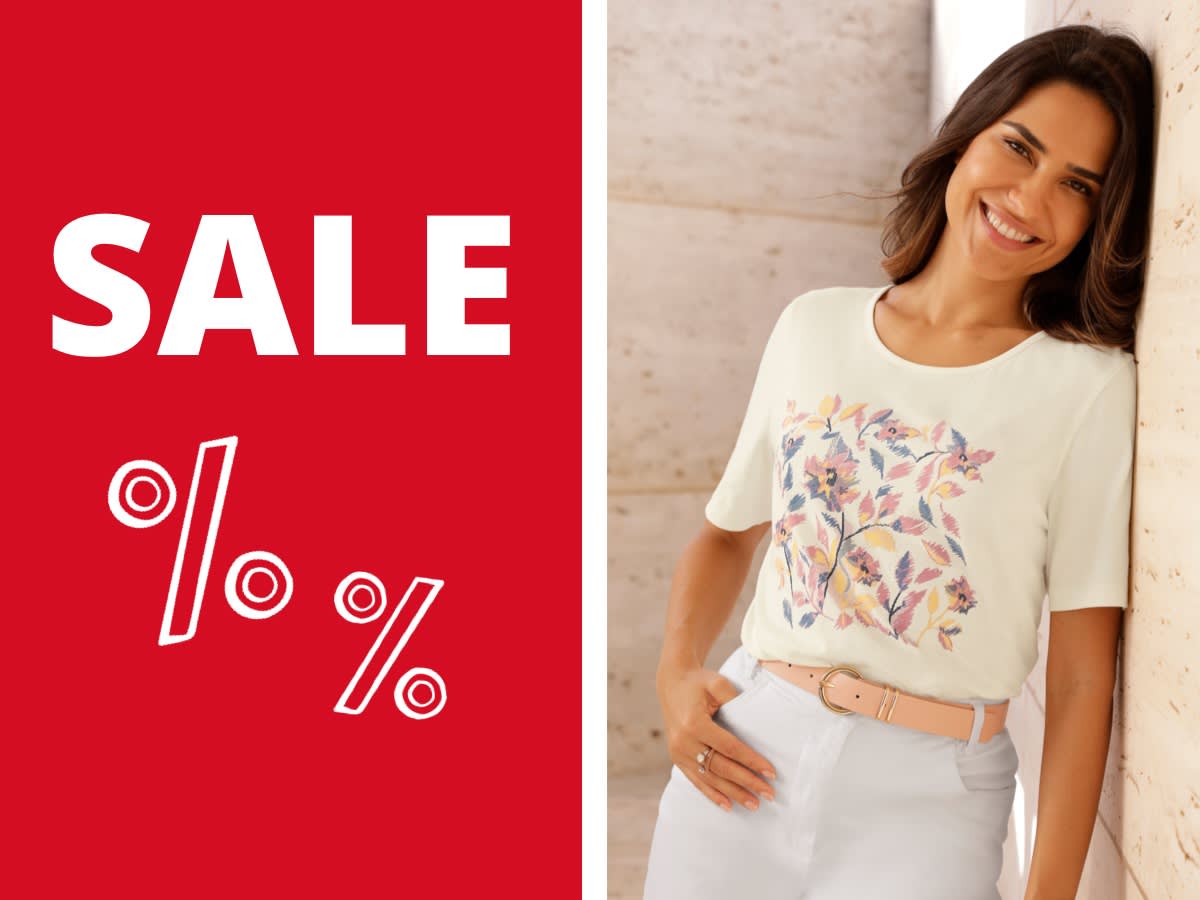 Een model draagt een crèmekleurig T-shirt met een bloemenpatroon, daarnaast zijn dezelfde T-shirts in lichtblauw en roze te zien.