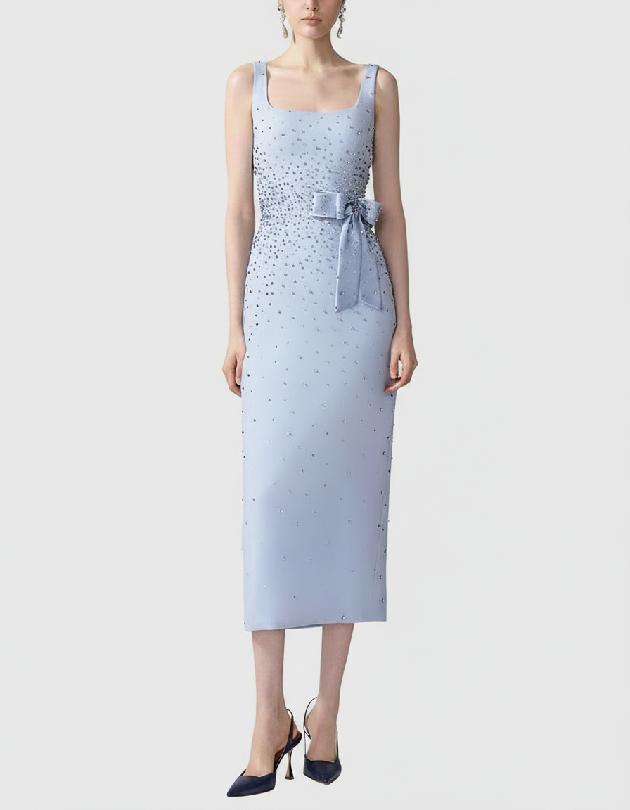 Woman in a light blue, sleeveless, knee-length dress with scattered embellishments and a bow belt.