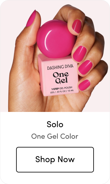 Close-up of a hand with magenta manicured nails called 'Solo' holding a Dashing Diva One Gel polish bottle, with a 'Shop Now' button below, labeled 'One Gel Color.'