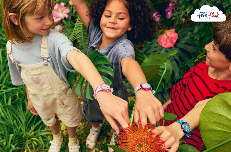 Kinder die eine Flik Flak Uhr am Handgelenk tragen spielen im Garten 