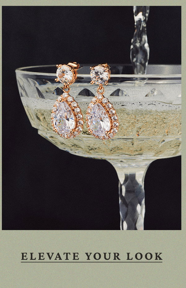 Teardrop crystal drop earrings in a rose gold setting hanging over the edge of a champagne coupe glass filled with bubbly. Text: ELEVATE YOUR LOOK.