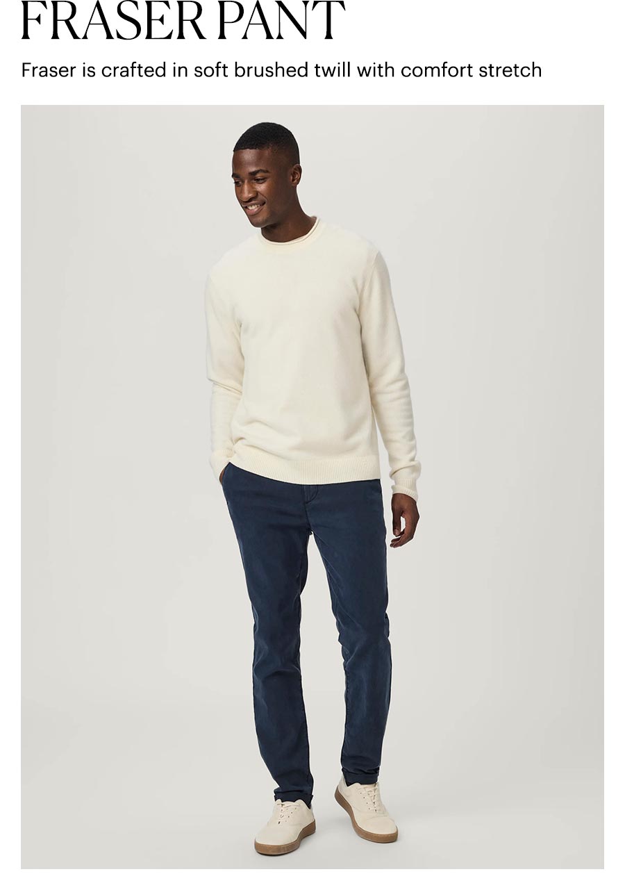 Fraser Pant - Fraser is crafted in soft brushed twill with comfort stretch. Featuring a man wearing dark navy cuffed trousers with a cream long-sleeve and beige sneakers.