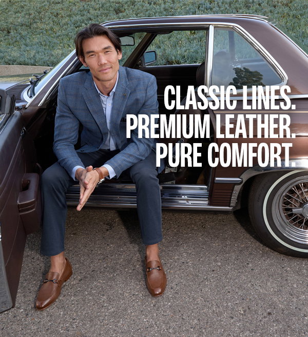 Man sitting in the open door of a classic car wearing a blue blazer, navy pants, and brown Higgins Bit Loafers. Text reads: 