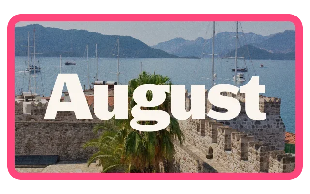 Scenic coastal harbour with calm blue water, sailboats, and mountains in the background, viewed over historic stone walls and a palm tree in the foreground. Large white text reading 'August' is prominently displayed across the center of the image. The image is framed by a bright pink border.