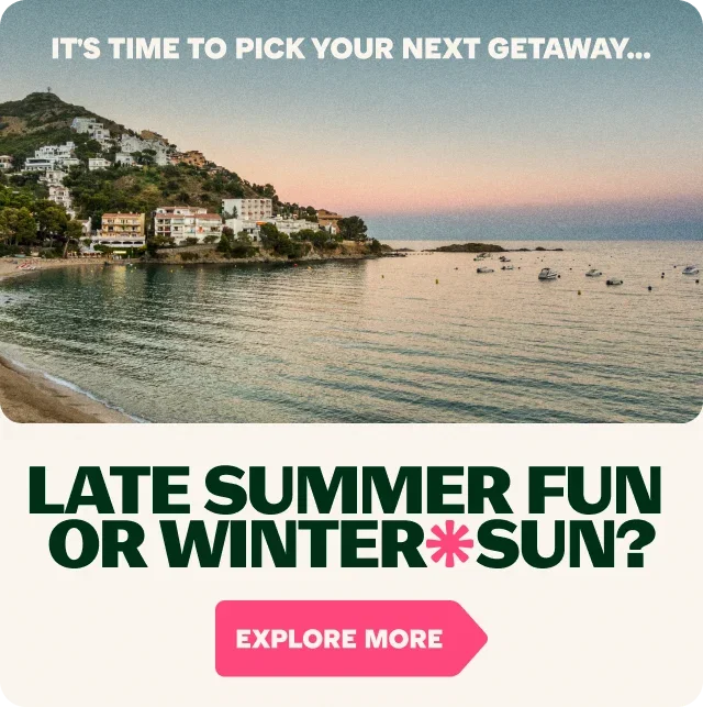 Scenic coastal destination at sunset featuring a peaceful bay, boats on the water and whitewashed buildings on a hillside. Text: 'IT'S TIME TO PICK YOUR NEXT GETAWAY...'