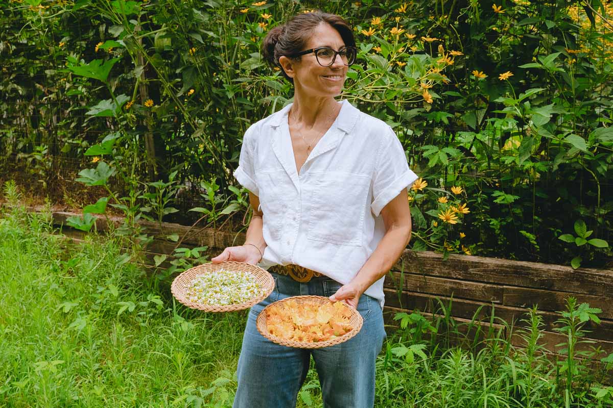 Annmarie holding herbs in a basic for the Divine Woman Elixir