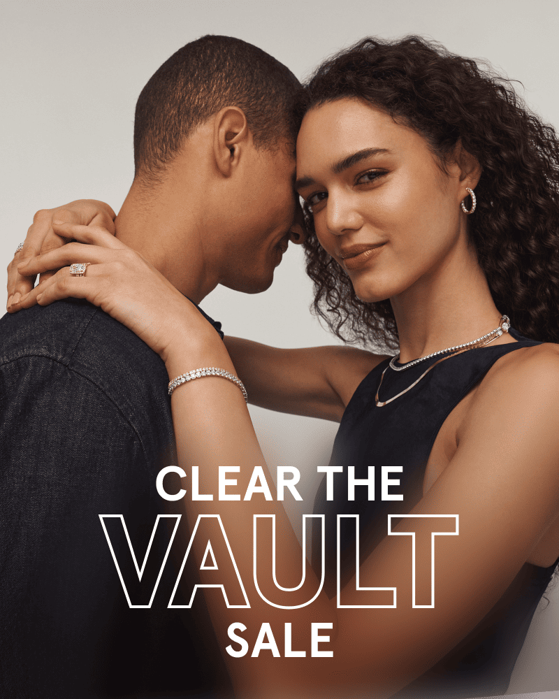 Woman embracing her partner while wearing hoops, necklaces, a diamond tennis bracelet and a ring. Clear the vault sale.