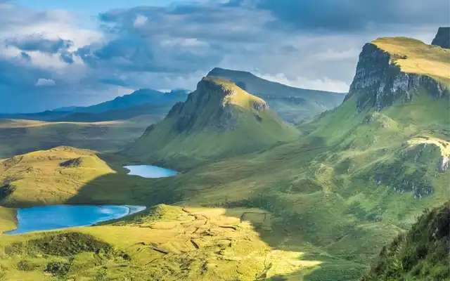 Vista panorámica del Quiraing en la Isla de Skye, con sus formaciones rocosas y valles verdes bajo un cielo nublado
