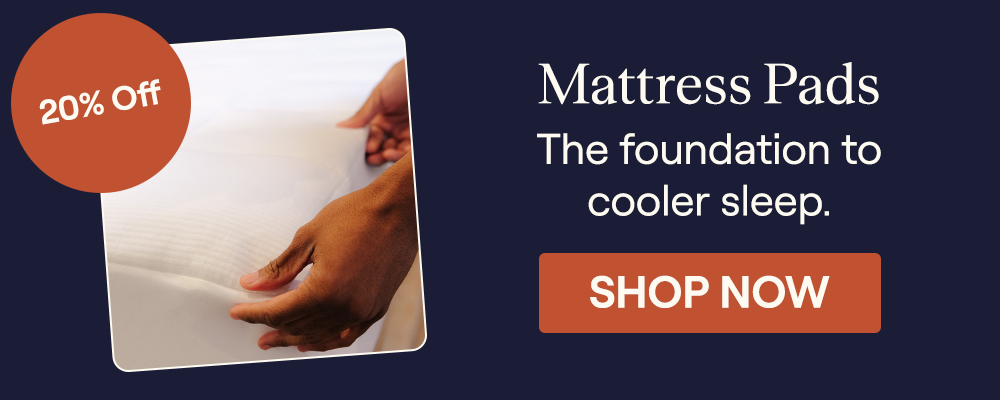 A close up of a man's hands putting the Performance Mattress Pad on a bed