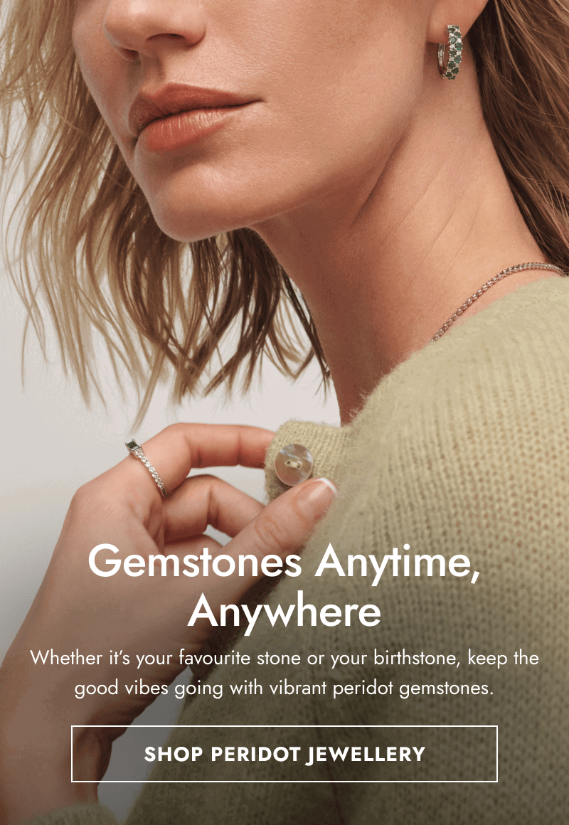 Woman in light green cardigan, necklace, green gemstone hoops and ring. Gemstones anytime, anywhere. Click shop peridot jewellery.