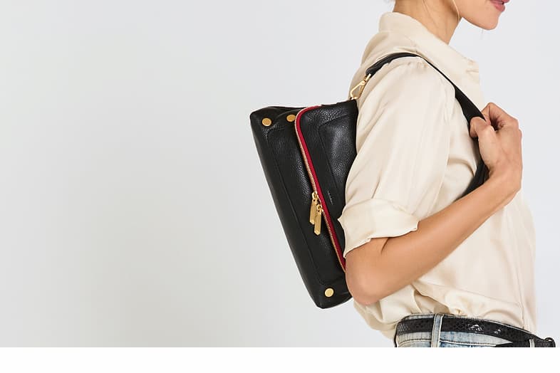 Side profile of the Hammitt Beverly Med in Black/Brushed Gold Red Zip, highlighting its slim silhouette, signature rivets, brushed gold hardware, and bold red zipper accent.