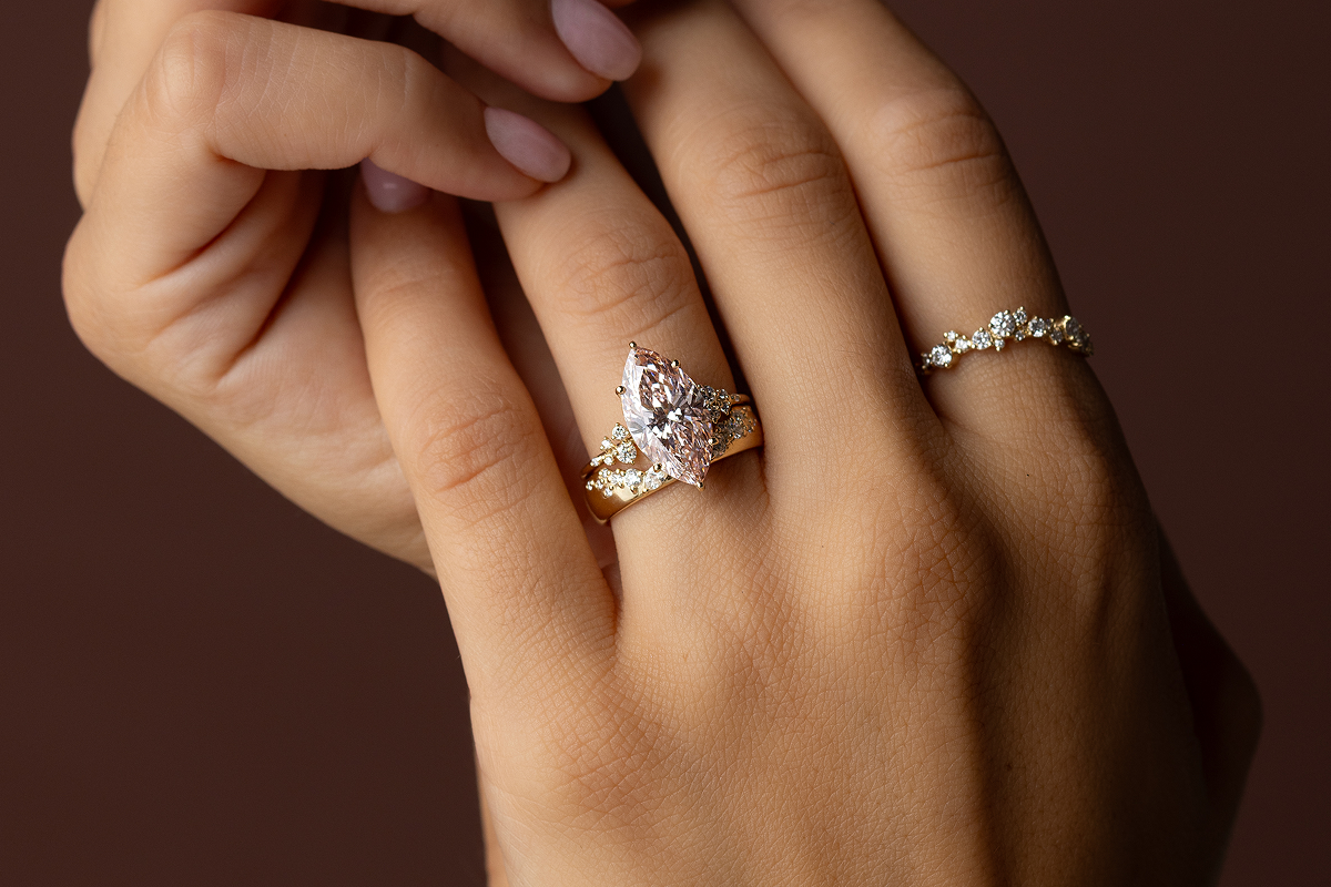 Photo features a model holding one hand in the other while wearing a marquise cut Snowdrift Ring paired with a Wide Snowdrift Band.