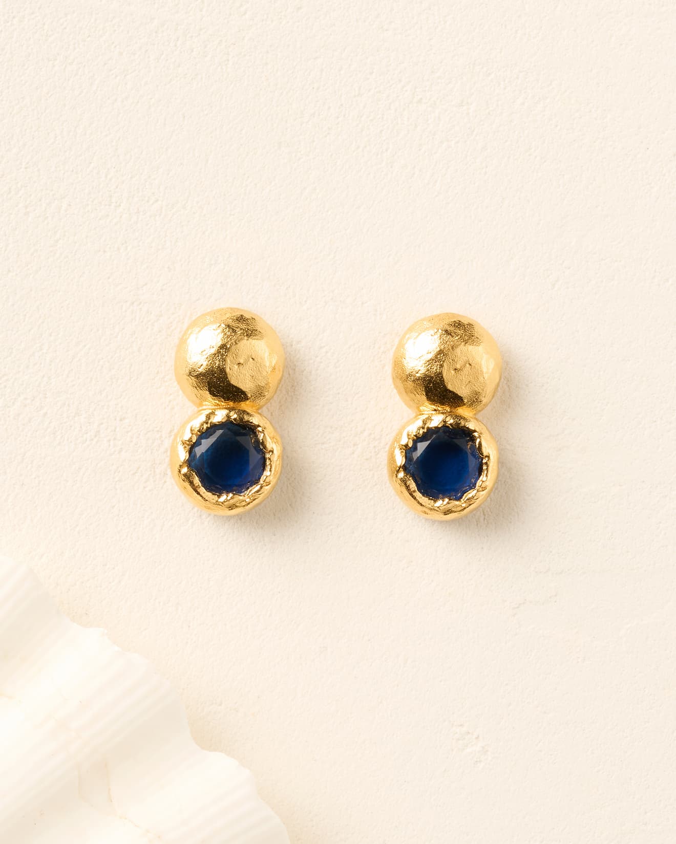 Petra earrings: gold stud earrings with a textured bead and a deep-blue round stone