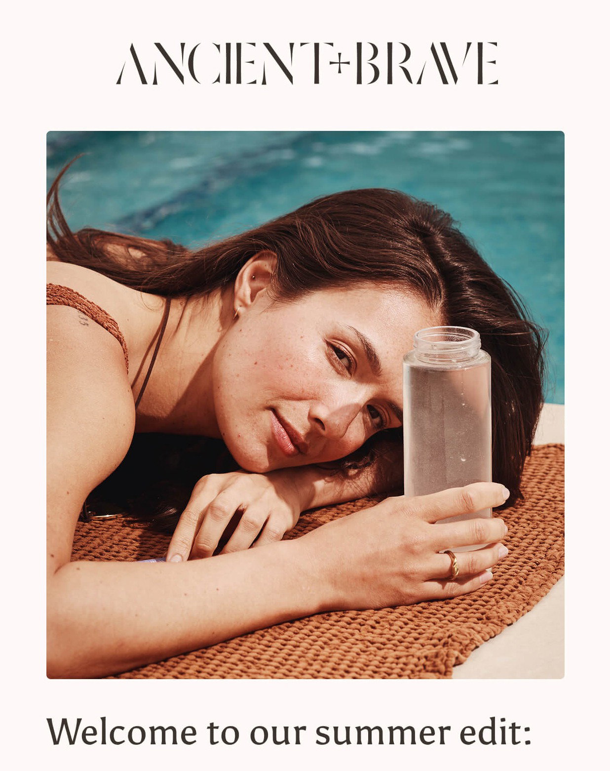 Woman lying poolside on a woven towel, resting her head on her arm while holding a bottle of Ancient + Brave collagen water. Welcome to our summer edit: