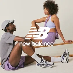 Dos personas con ropa deportiva sentadas y hablando cerca de un banco de madera en un espacio interior brillante y minimalista.