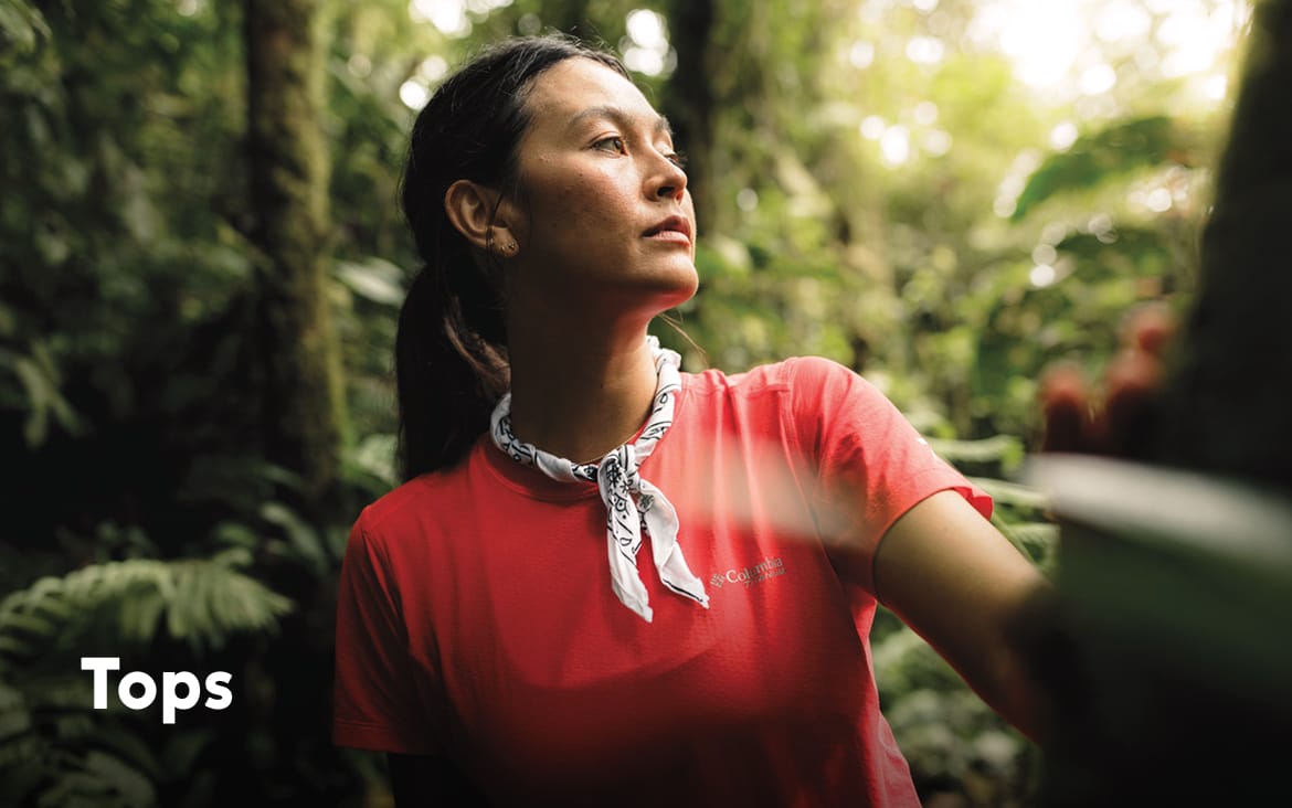 A woman wearing a red short sleeve shirt in a forest with text: Tops