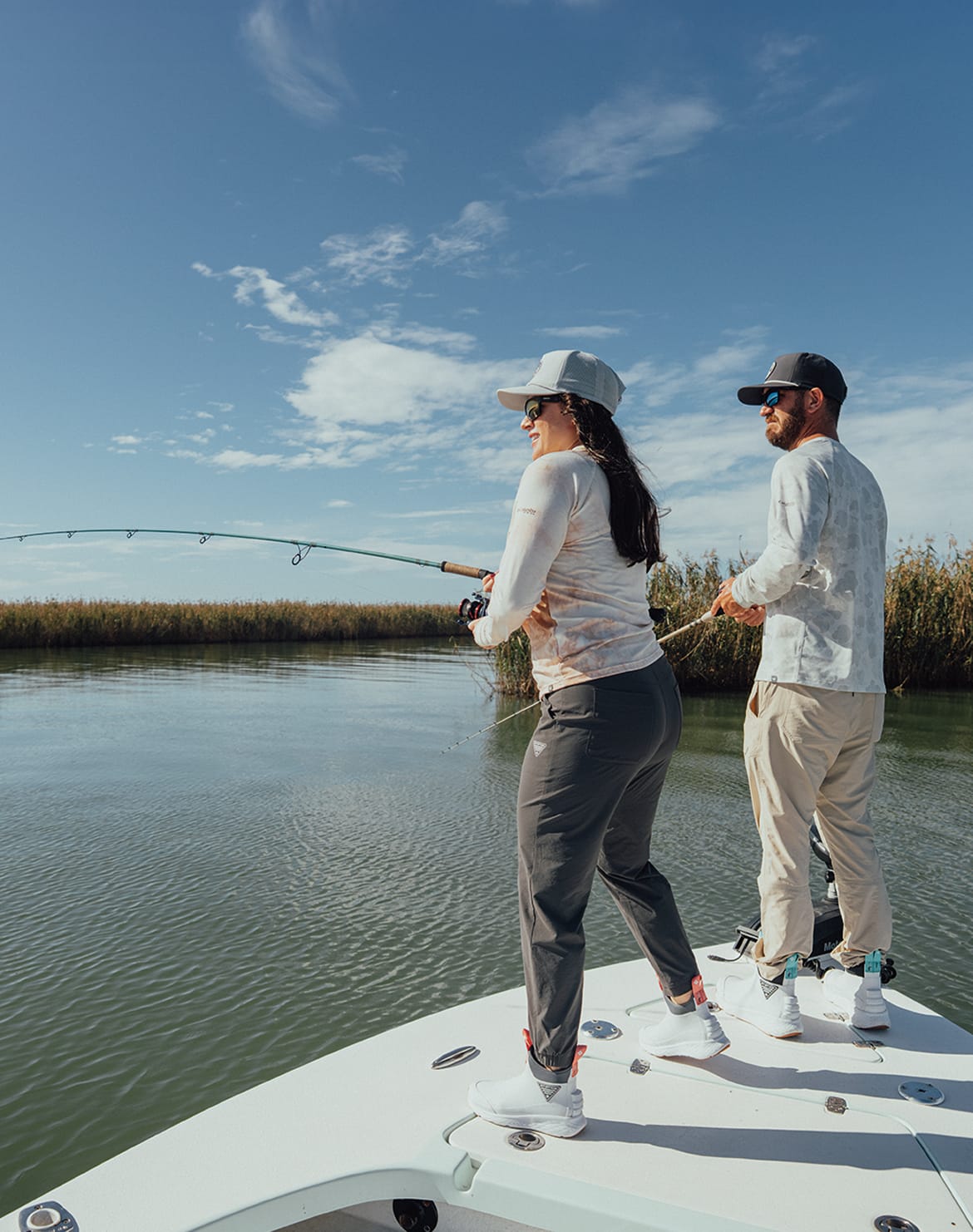 Two anglers on a boat, holding fishing rods.