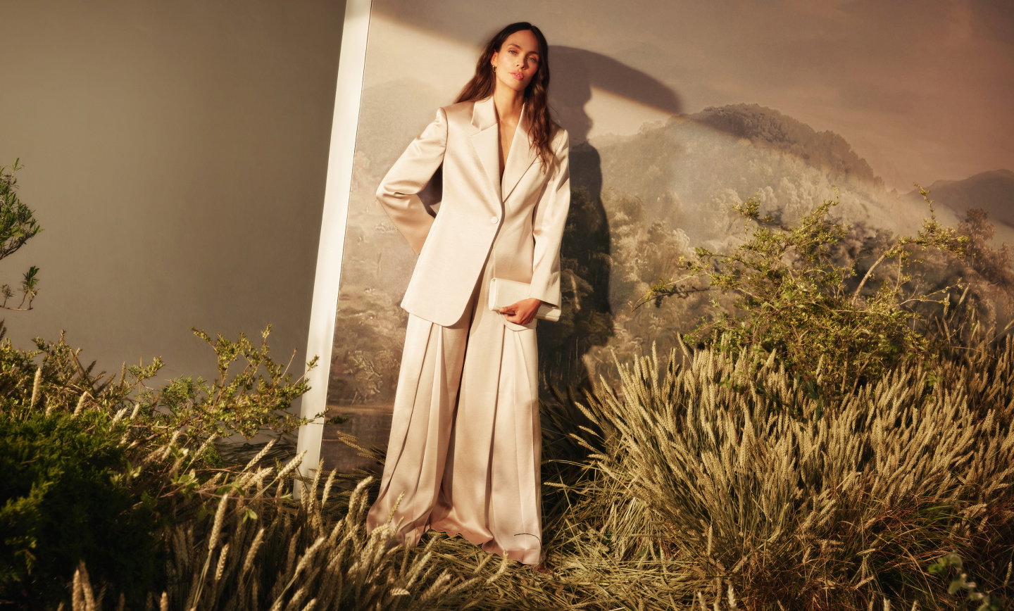 Cream tailored blazer and wide-leg trousers, styled against a mountain landscape backdrop