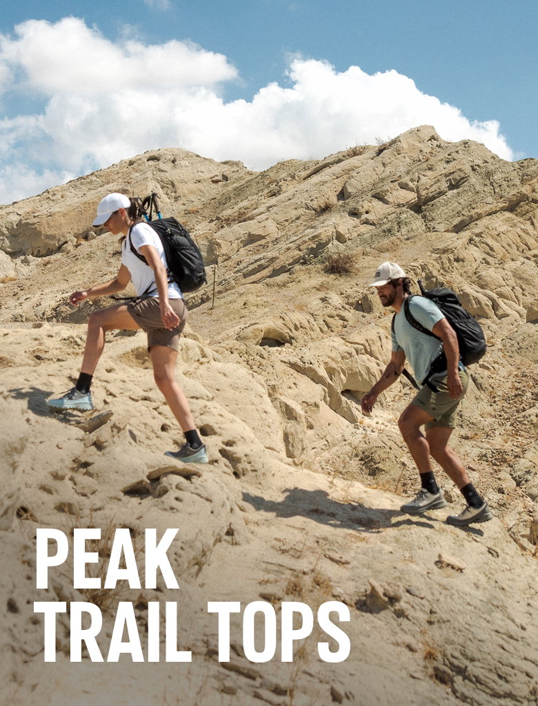Peak Trail Tops. Image of a woman and man hiking in arid terrain. 