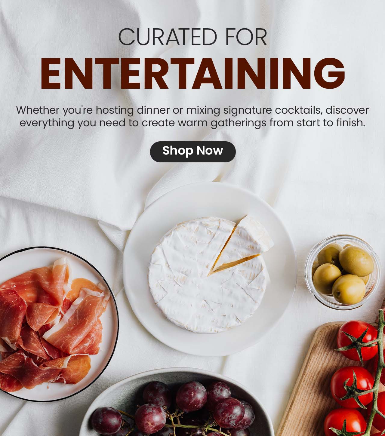 Charcuterie board with cheese, olives, tomatoes, grapes, and cured meats promoting entertaining essentials