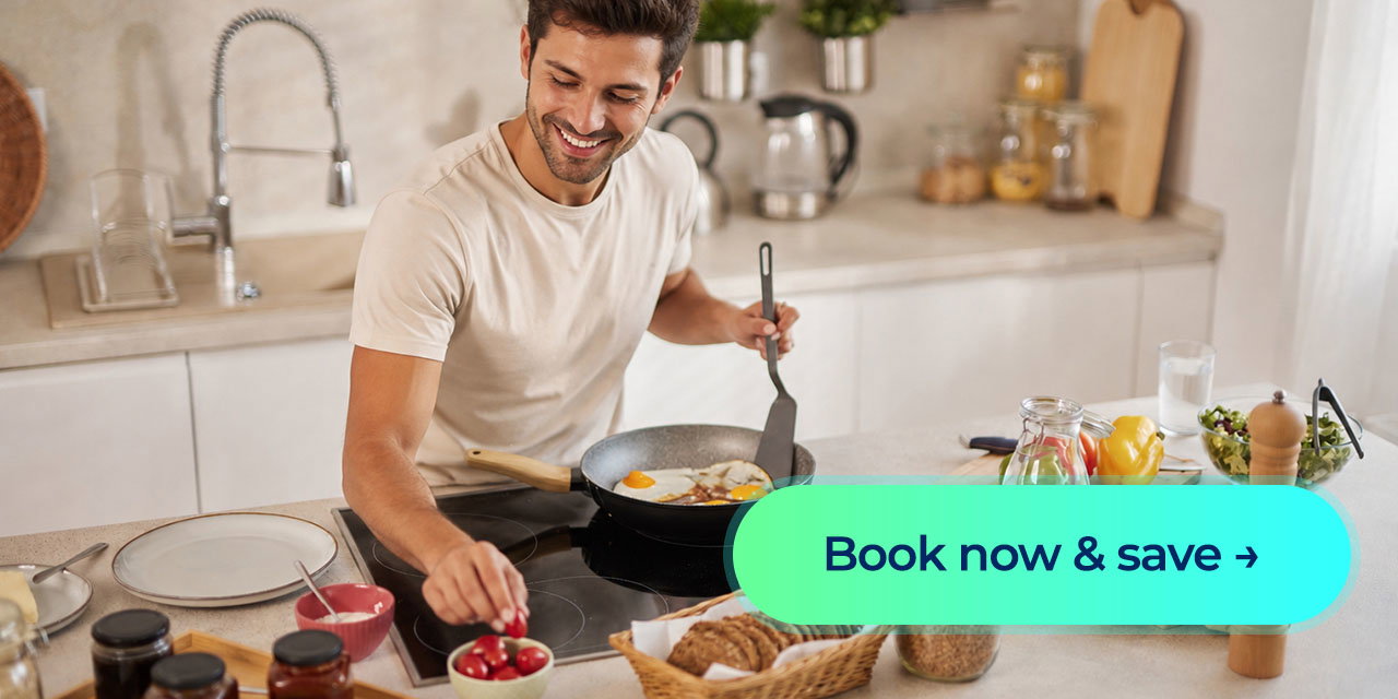 A smiling man cooks breakfast for his family, with a “Book now & save” call-to-action