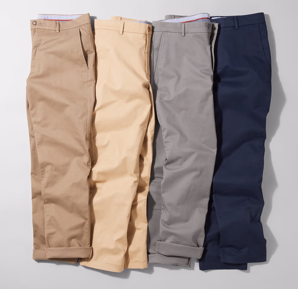 Four pairs of men's chino pants in shades of khaki, beige, grey, and navy, folded and displayed side-by-side on a light grey background.