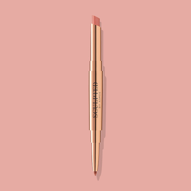 A dual-ended gold lip pencil with a pink and brown tip on a pink background.