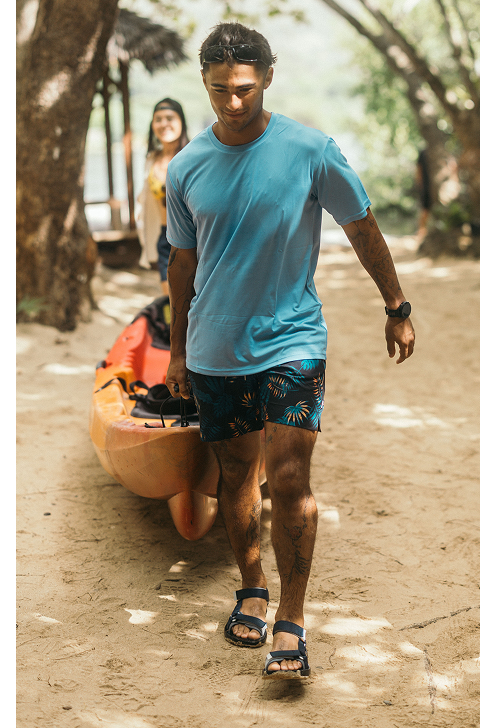 Two people pulling a canoe across sand, wearing Teva sandals.