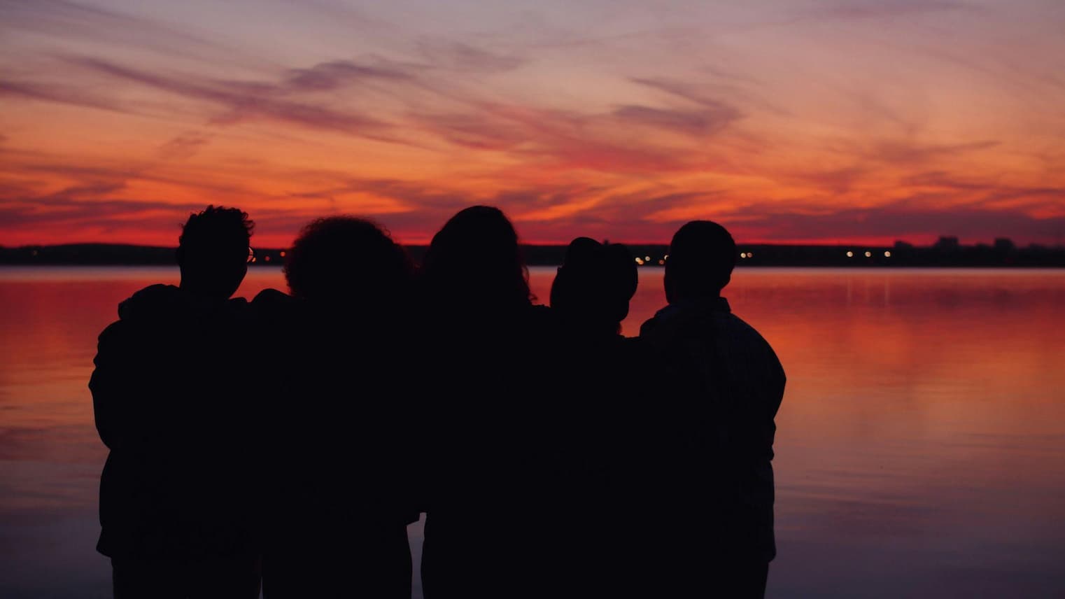 People together beside the water at sunset
