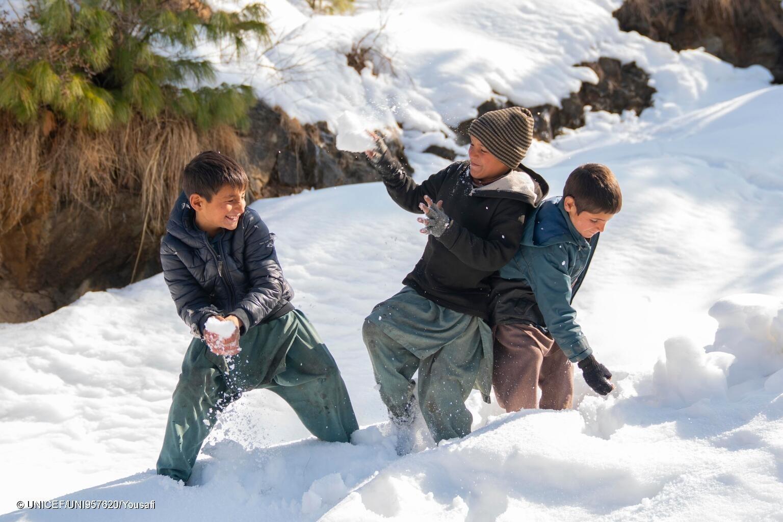 As snow falls, Faisal, 8, and his friends chase one another through a flurry of snowballs and laughter.