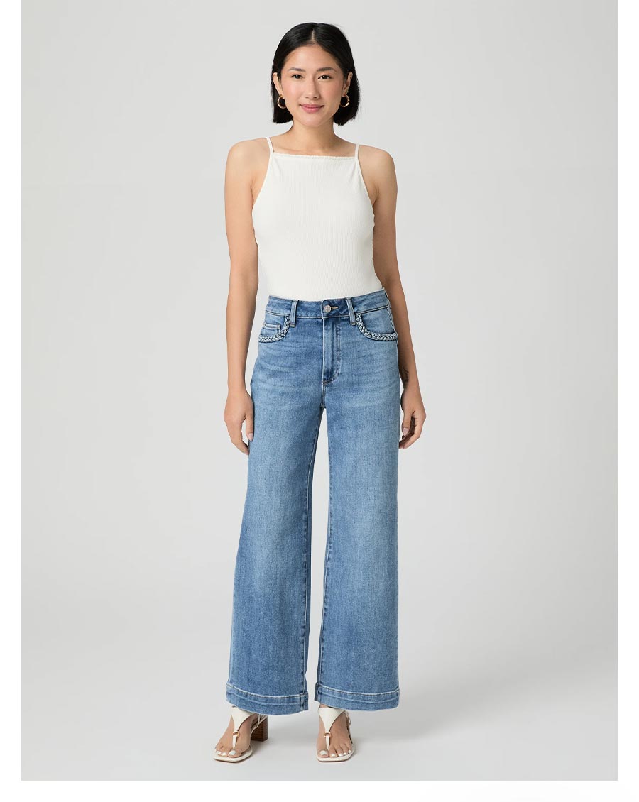 Woman wearing a pair of medium wash high rise wide leg jeans with a white tank