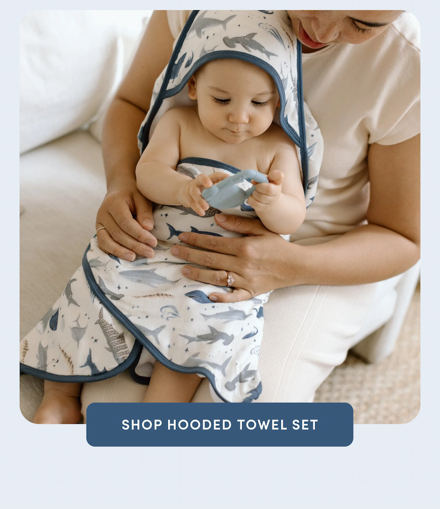 baby wrapped in a shark printed towel sitting on his mom's lap