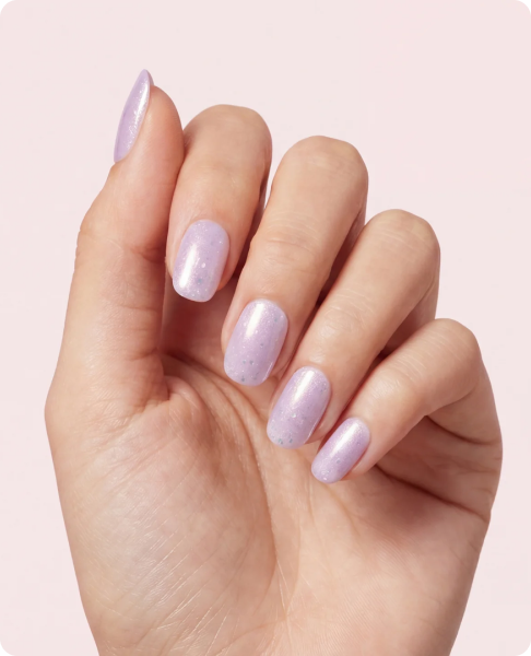 Close-up of a hand with shimmery lavender-purple manicured nails featuring a subtle glitter finish.