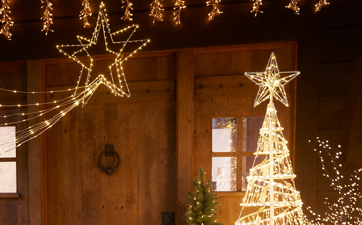 Outdoor Christmas light display with illuminated star decorations and a glowing tree silhouette.