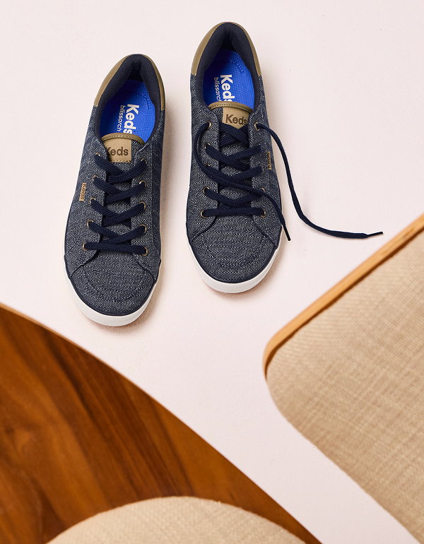 A beige background with peeks of furniture and an overhead view of the Center III Herringbone Chambray Lace-Up in navy/cognac. 