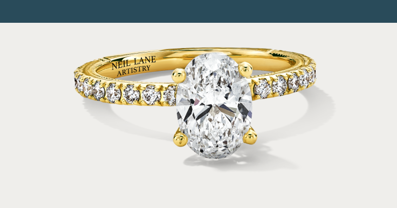 An oval diamond engagement ring with pavé band in yellow gold.