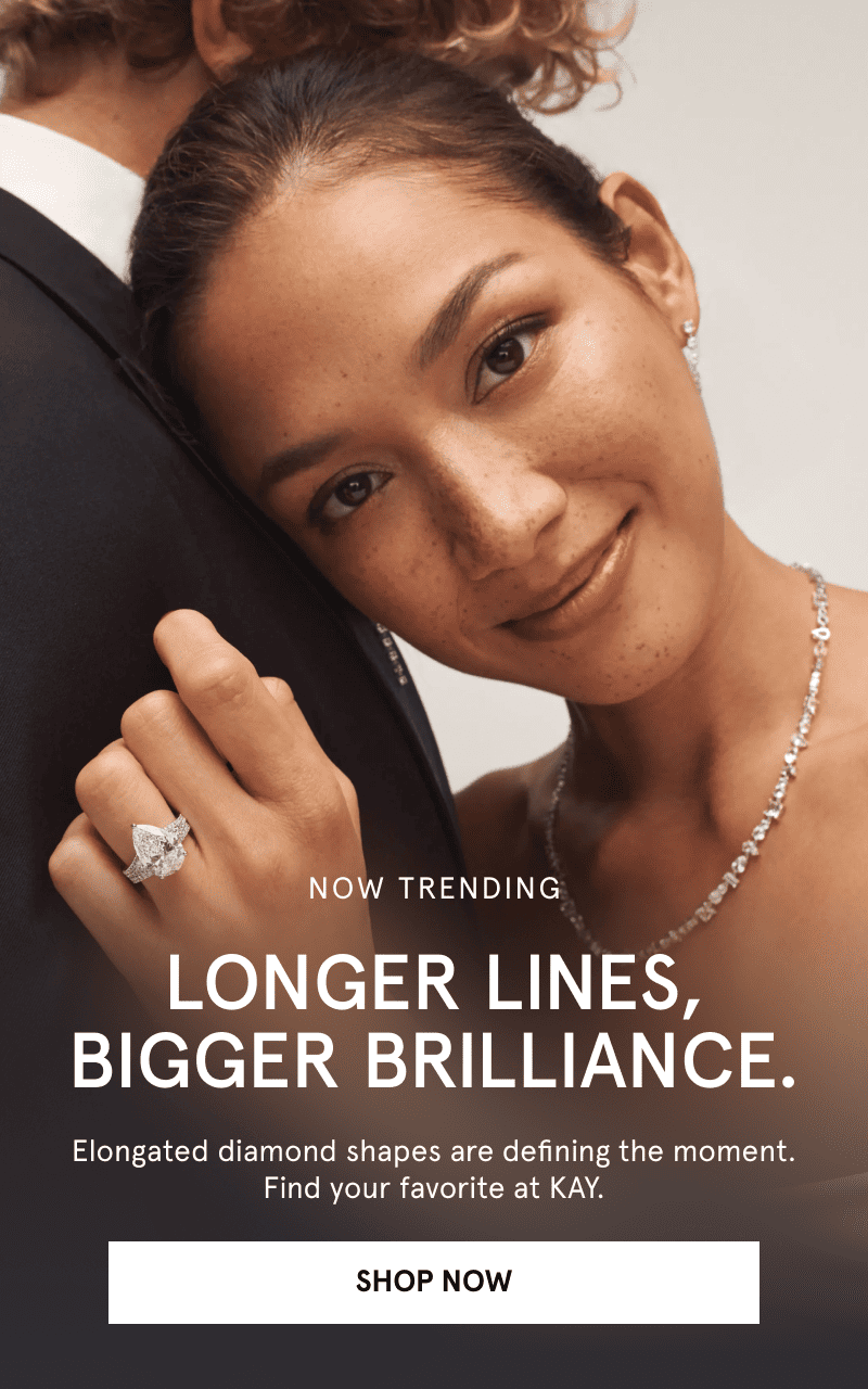 A model wearing diamond jewelry, leaning against man. Now trending. Bigger brilliance. Defining elongated shapes. Click shop now.
