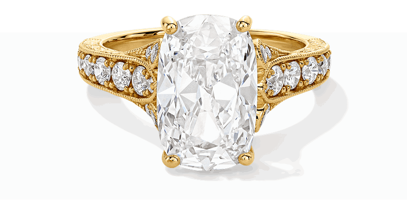 Yellow gold cushion-cut engagement ring, with four-prong setting and diamonds along the band.