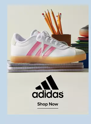 Adidas. Shop shoes. A white sneaker with pink strips on a note pad and other school supplies.