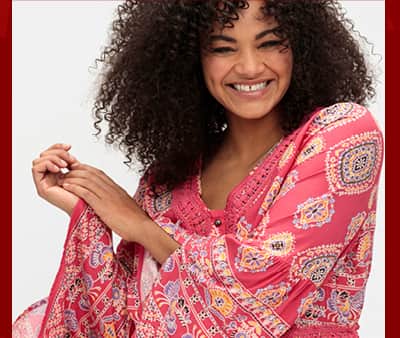 Ein Model trägt eine rot-gemusterte Longbluse mit Trompetenärmeln