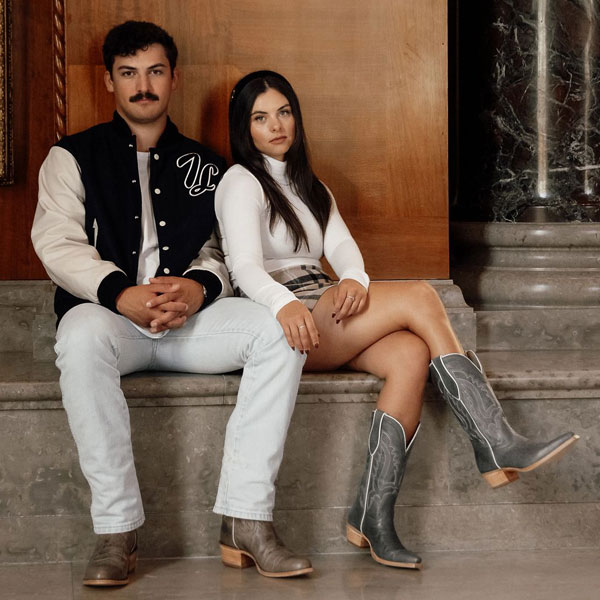 Two people sitting wearing Tony Lama boots and apparel.