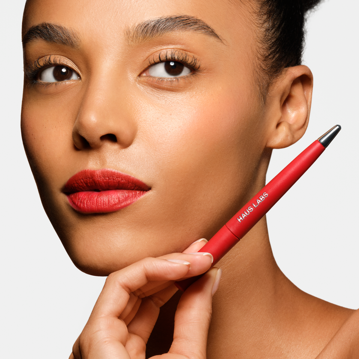 A model holding and wearing Haus Labs le monster lip crayon