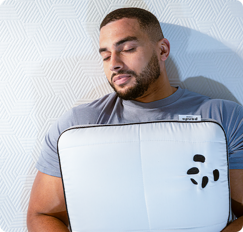 Man lying on a bed holding a Panda London Hybrid Bamboo Pillow