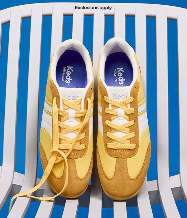 A pair of Revival Nylon/Suede Lace-Ups in yellow with white stripes sitting on a white plastic beach chair.