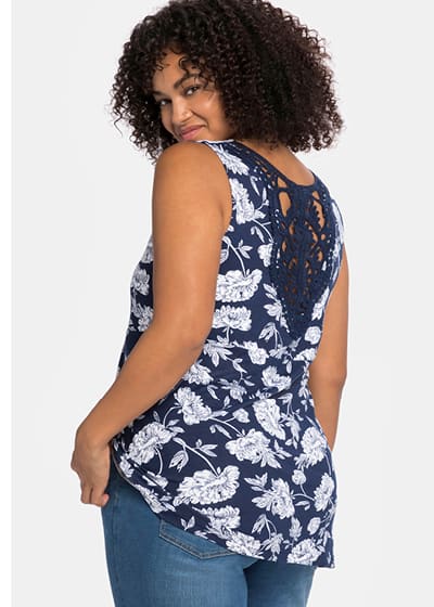 Ein Model trägt ein blau bedrucktes Longtop mit floralem Alloverdruck und Crochet-Spitzeneinsatz hinten