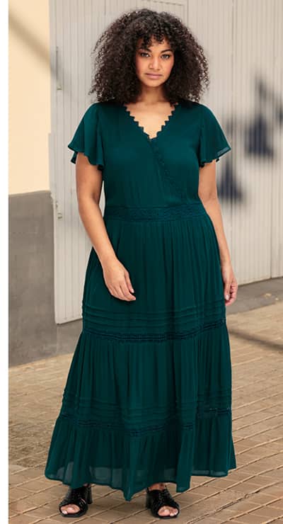 Ein Model trägt ein petrol farbenes Maxikleid in Wickeloptik mit V-Ausschnitt in Wickeloptik, mit Flügelärmel