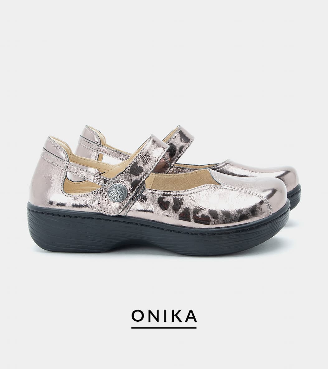 Pair of metallic silver Mary Jane shoes with a subtle leopard spot overlay pattern, decorative side buttons, and dark gray platform soles. Product name "ONIKA" printed below.
