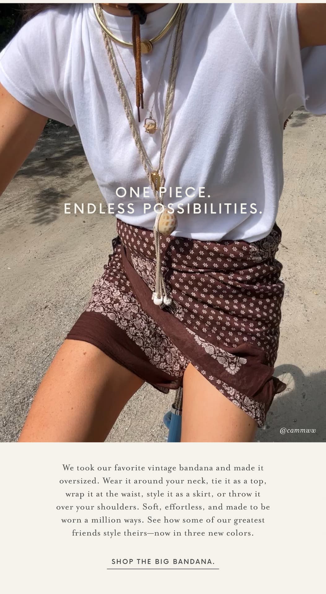 Lifestyle image of a person riding a bicycle wearing an oversized white tee styled with layered necklaces and a brown oversized bandana wrapped at the waist like a skirt. Overlay text reads, "One Piece. Endless Possibilities." Below, copy highlights the versatility of The Big Bandana—wear it around your neck, as a top, at the waist, as a skirt, or over your shoulders—and introduces three new colors. A button reads, "Shop The Big Bandana."